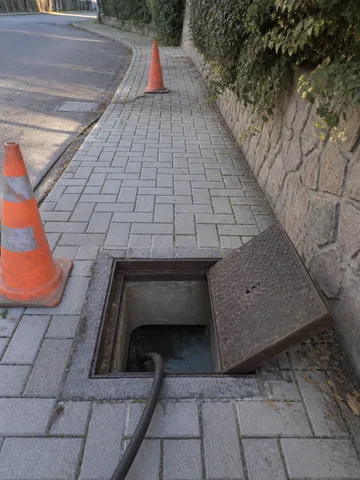 Arqueta de saneamiento abierta con manguera de alta presión durante un desatasco