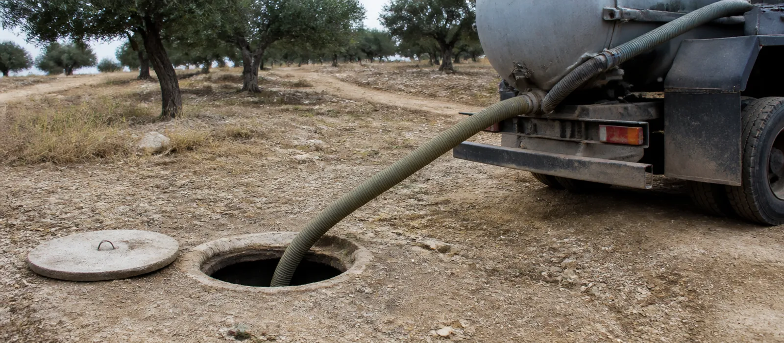 Fosa séptica de una parcela rural abierta con manguera de aspiración conectada a una cisterna